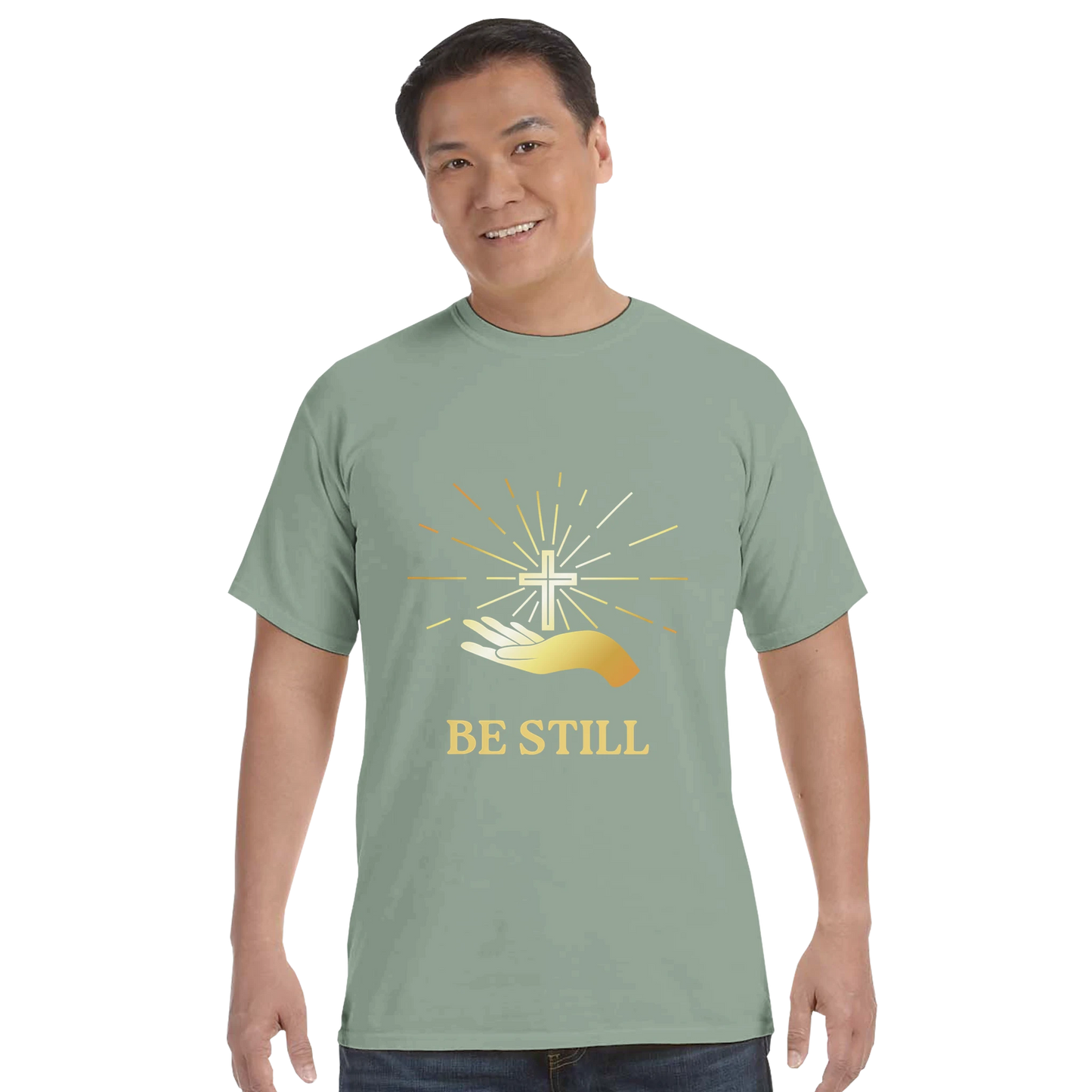 Light green Christian graphic t-shirt featuring a hand and a cross design with 'Be Still' text