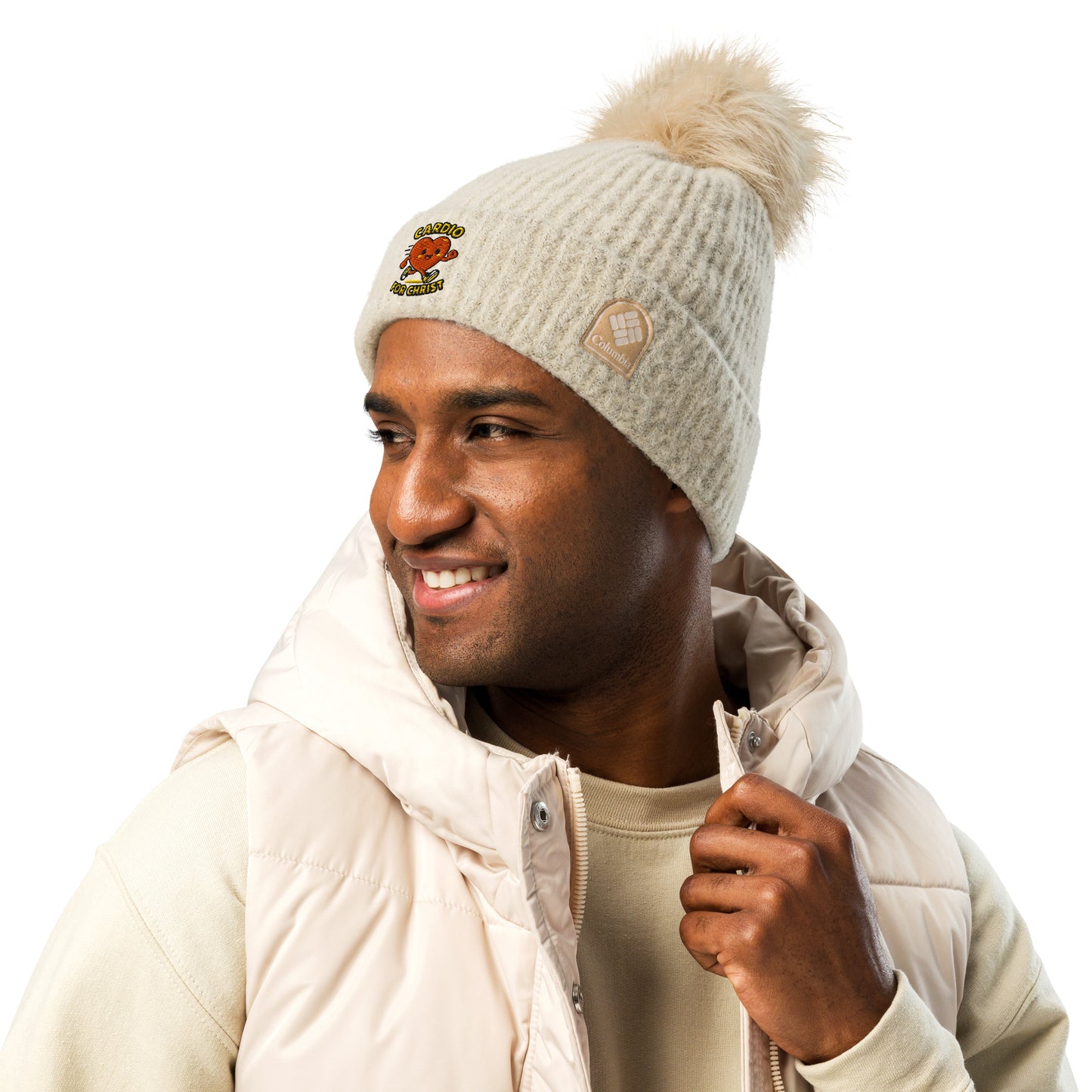 Spirit Wear beige Christian winter beanie with pom-pom worn by smiling man in light jacket