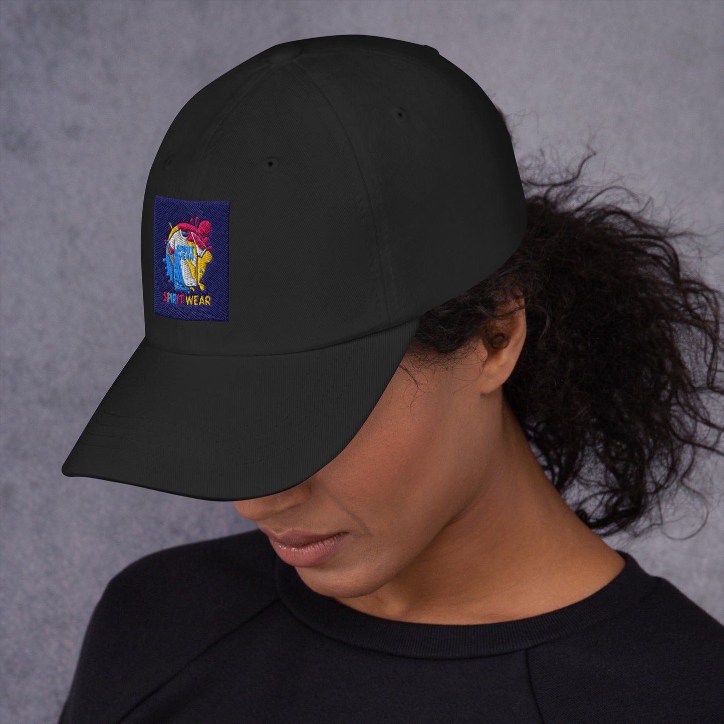 Black Christian ball cap with colorful Spirit Wear logo patch worn by woman with curly hair