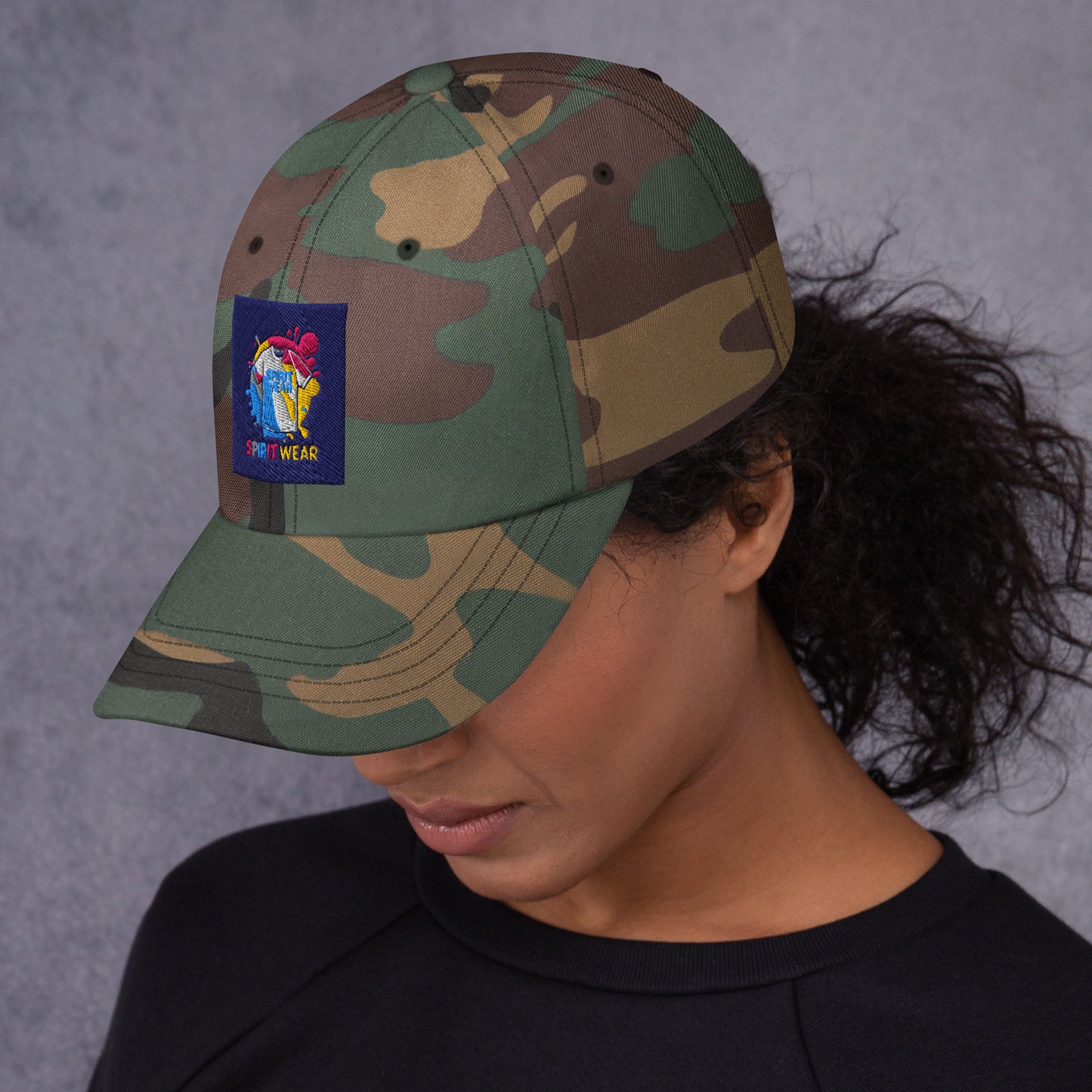 Spirit Wear camo Christian ball cap with colorful embroidered logo worn by woman with curly hair