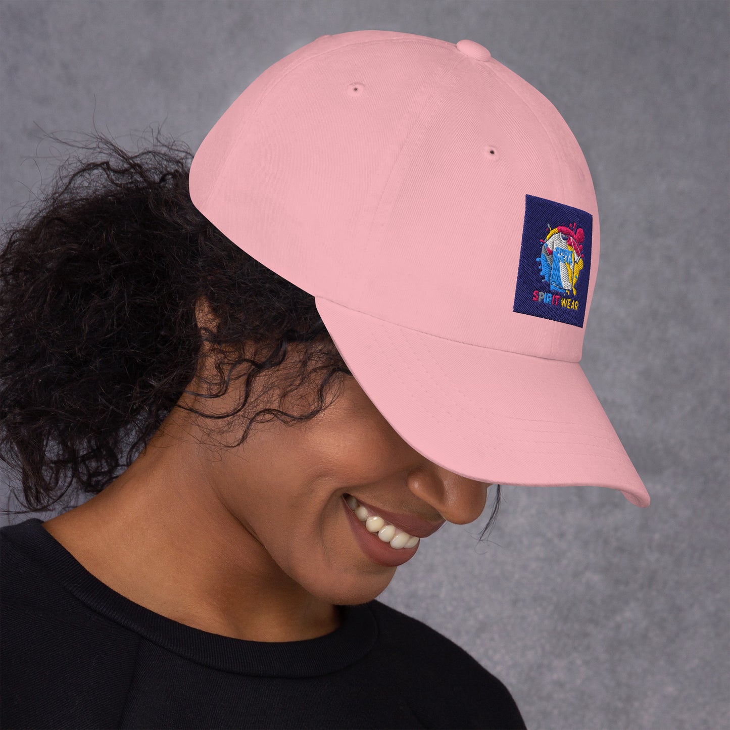 Pink Christian ball cap by Spirit Wear worn by smiling woman with curly hair and black shirt