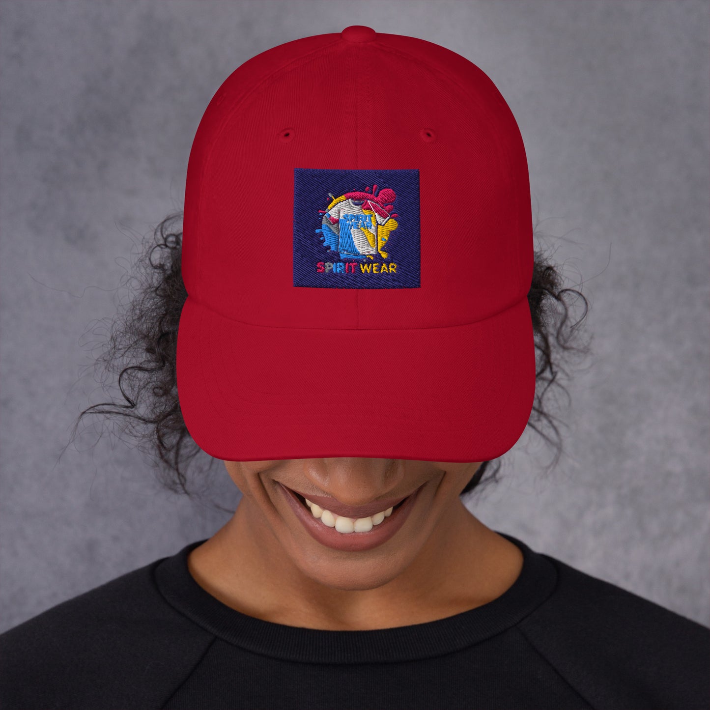 Red Christian ball cap by Spirit Wear with colorful embroidered logo on front worn by smiling person