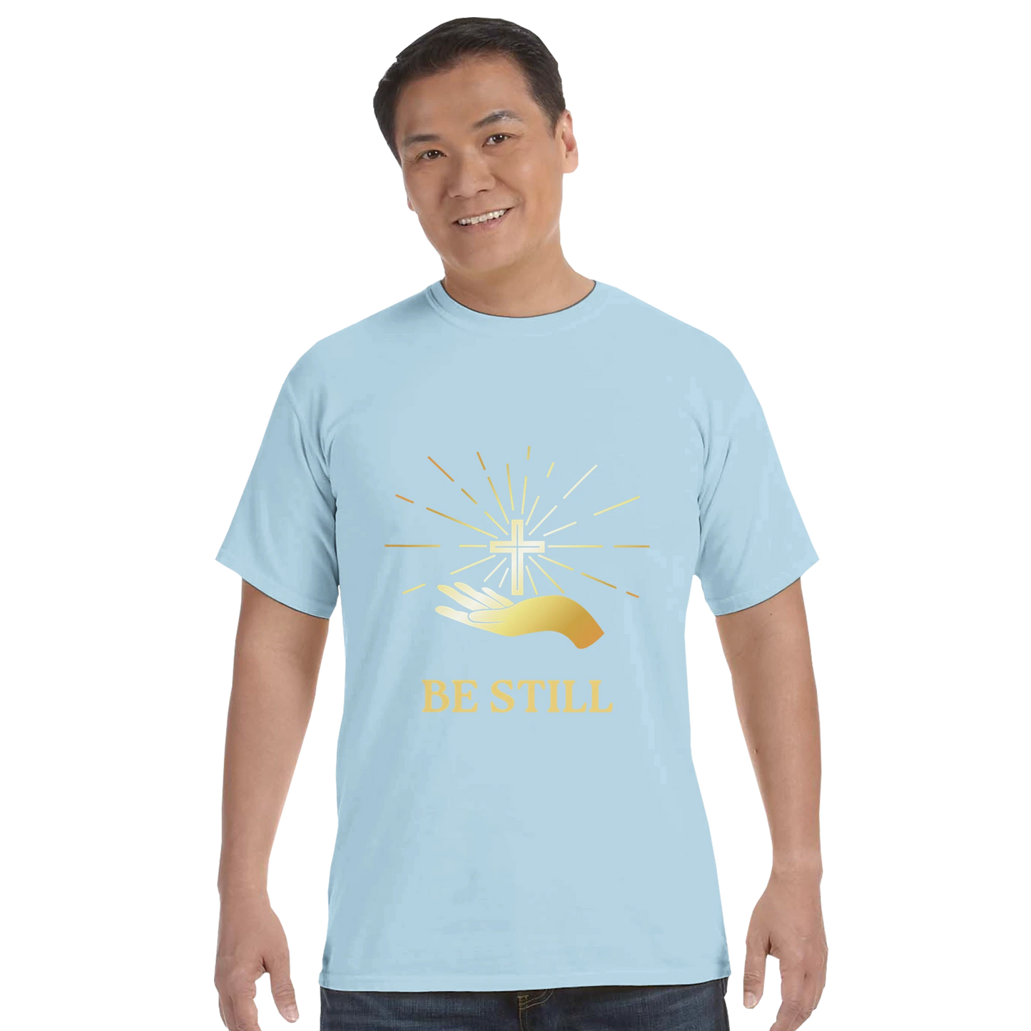 Light Blue Christian graphic t-shirt featuring a gold hand and cross design with the words Be Still