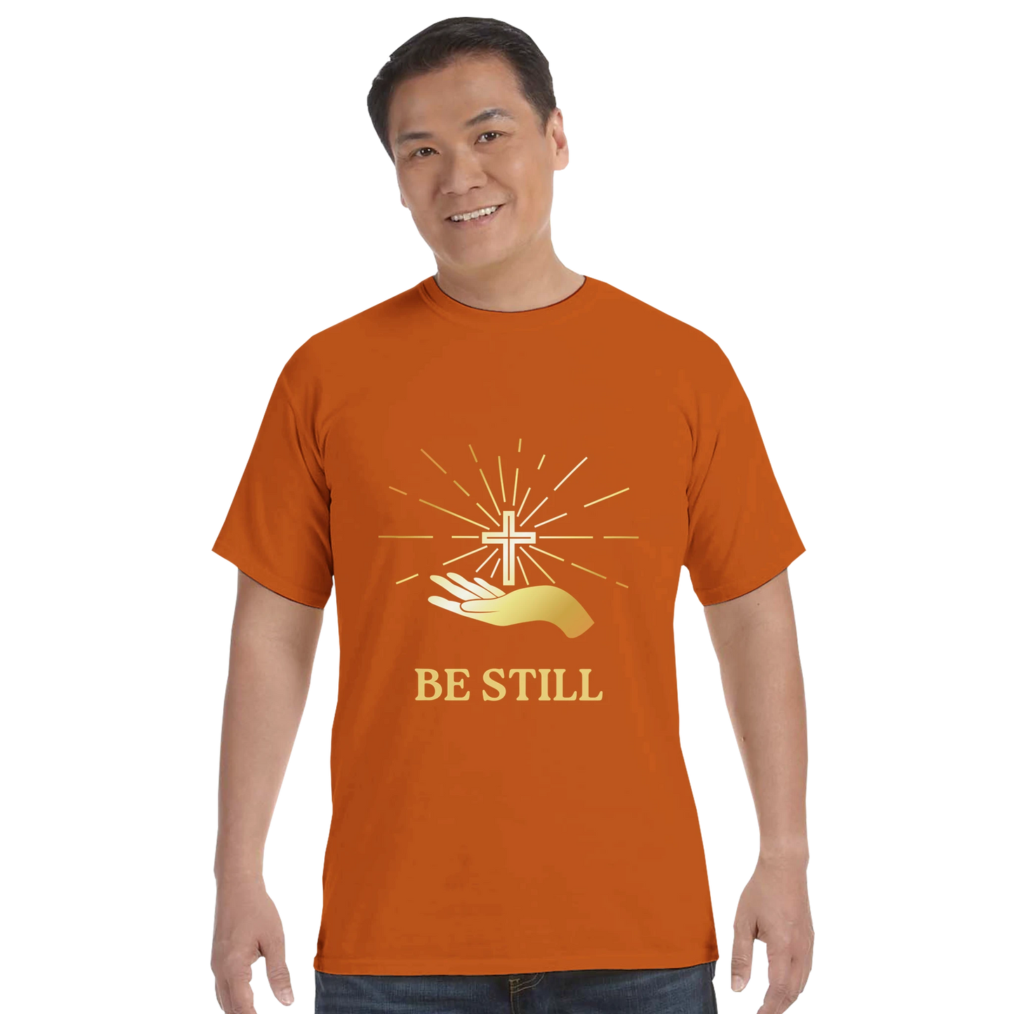 Orange Christian graphic t-shirt featuring a cross and hands with the text 'Be Still'
