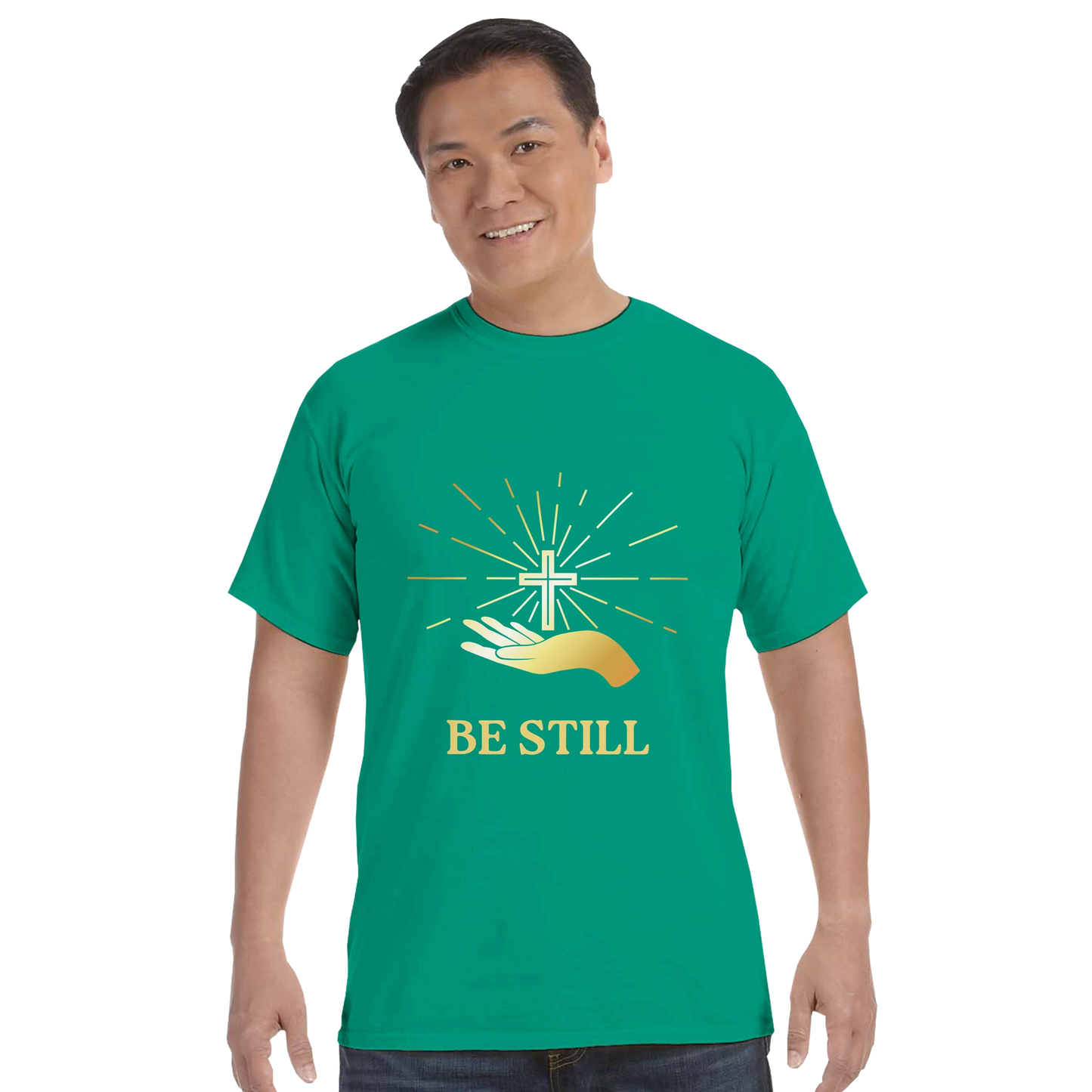 Christian graphic t-shirt featuring hands and a cross with the text Be Still in vibrant colors