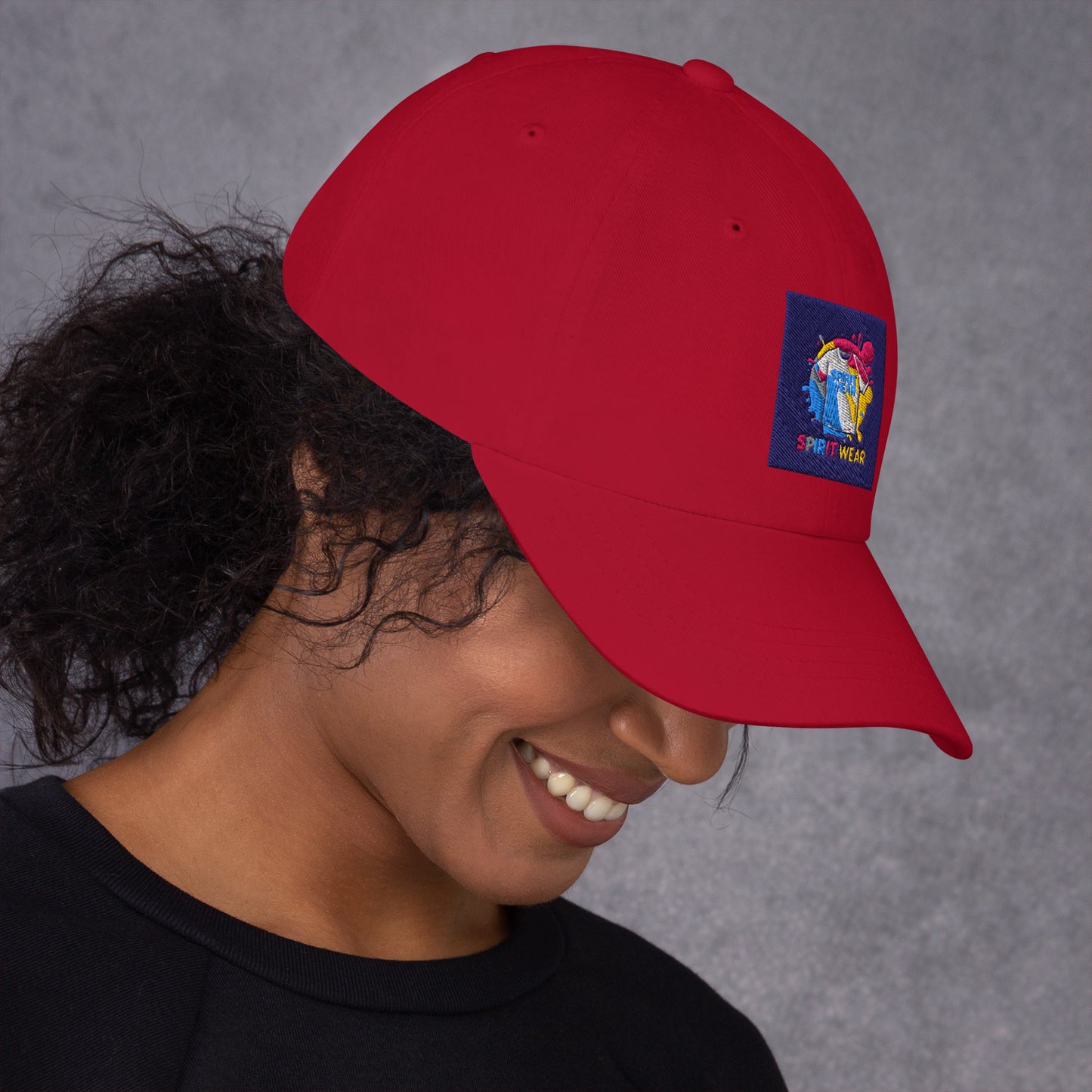 Red Christian ball cap by Spirit Wear with colorful embroidered logo worn by smiling woman