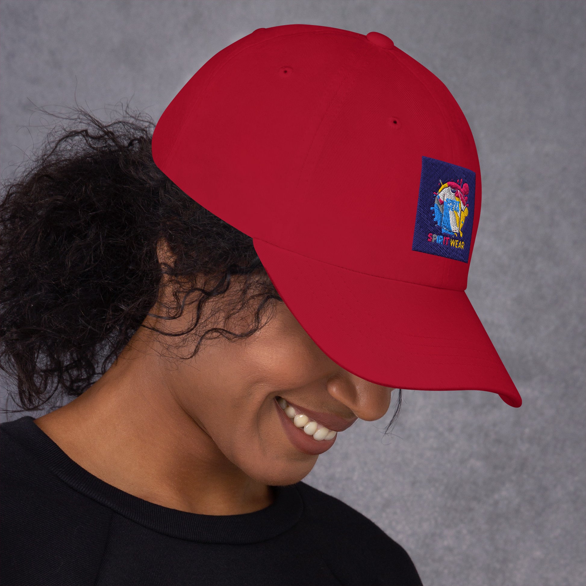 Red Christian ball cap by Spirit Wear with colorful embroidered logo worn by smiling woman