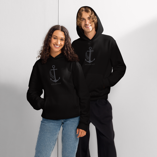 Two adults modeling black oversized religious hoodie for adults with anchor emblem and front kangaroo pocket