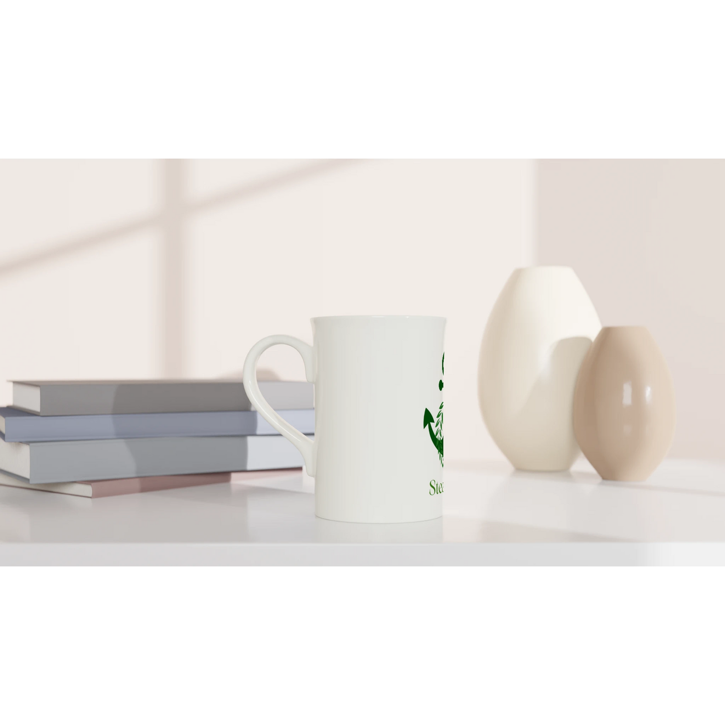 Spirit Wear Peace Pack Collection slim mug white ceramic with green logo on desk beside stacked books and decorative vases