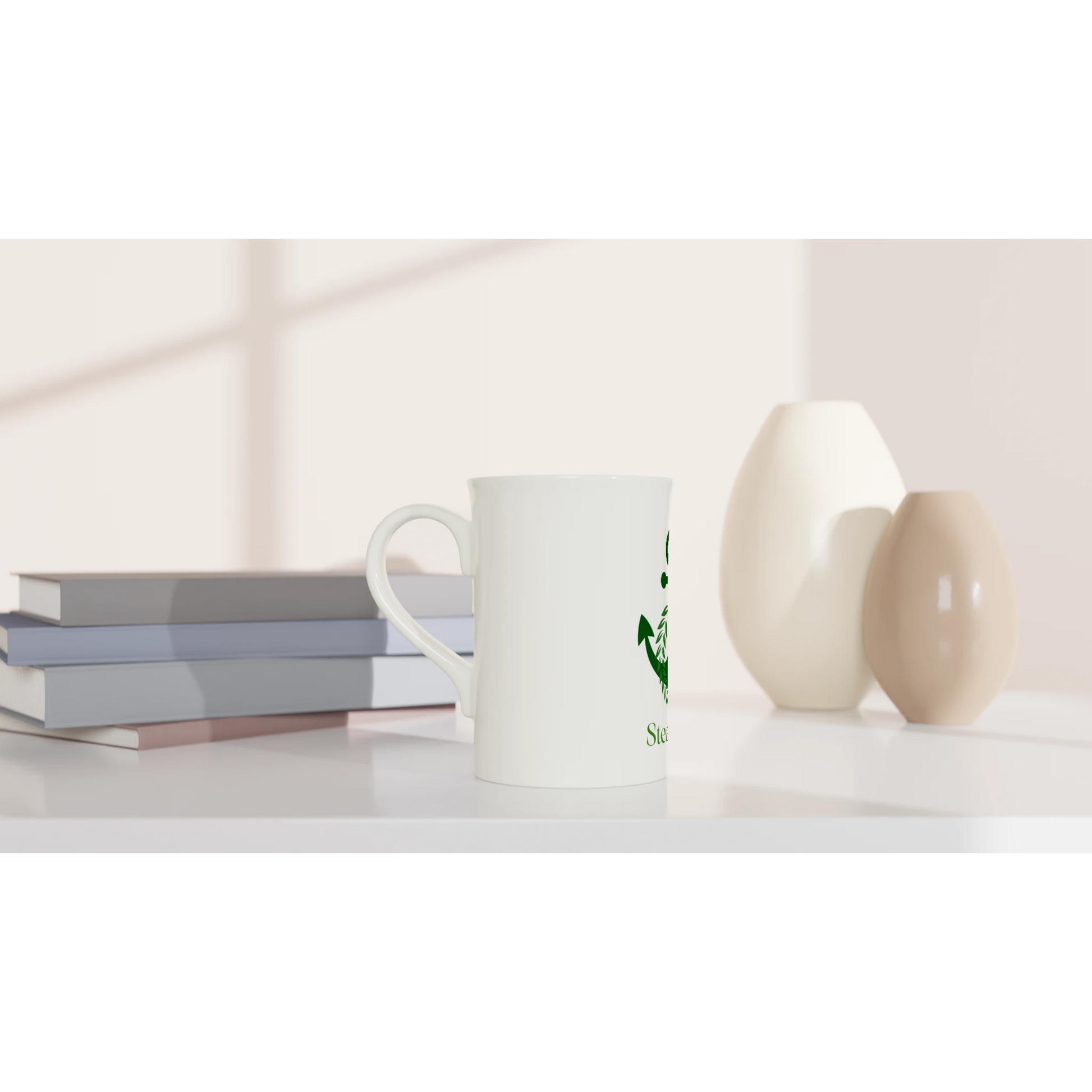 Spirit Wear Peace Pack Collection slim mug white ceramic with green logo on desk beside stacked books and decorative vases
