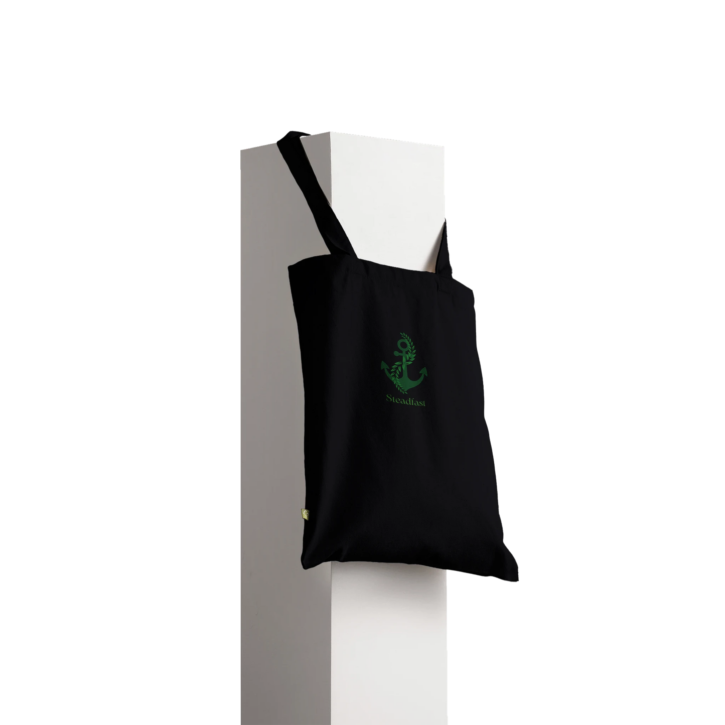 Black canvas Spirit Wear peace pack collection tote with green anchor logo hanging from white pedestal